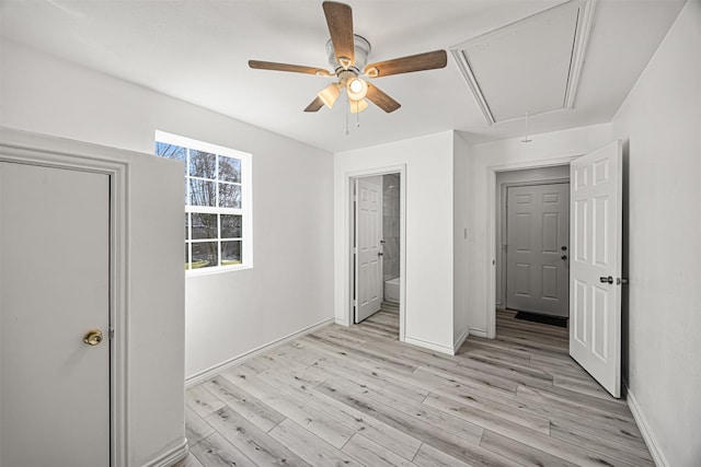 unfurnished bedroom with baseboards, a ceiling fan, attic access, and light wood-style floors