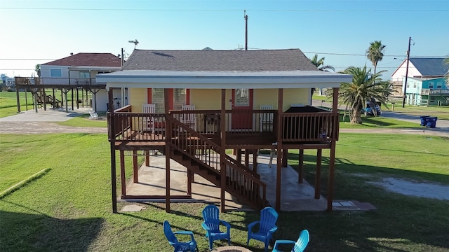 exterior space featuring stairs, a shingled roof, a lawn, and a porch