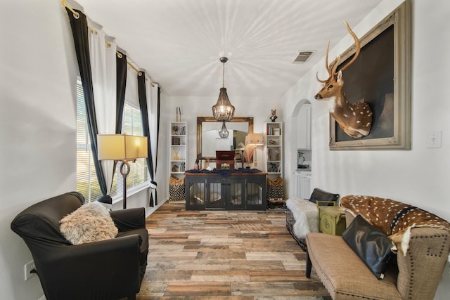 living area featuring arched walkways, wood finished floors, and visible vents