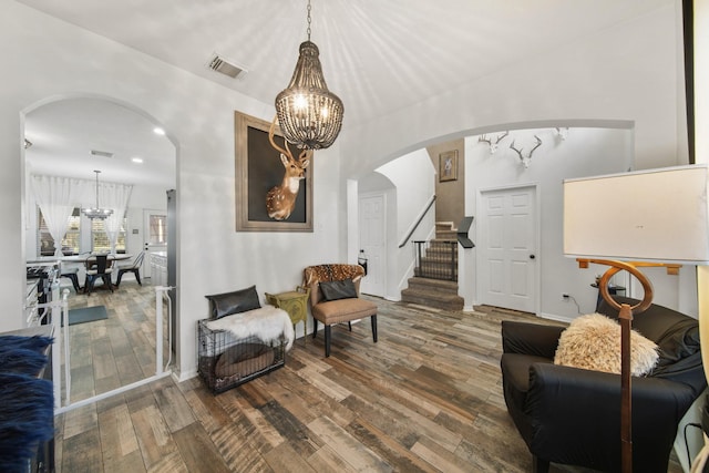 sitting room featuring visible vents, stairs, a chandelier, and wood finished floors