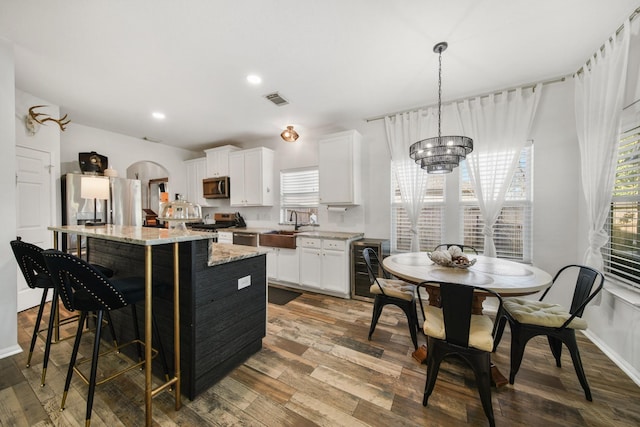 kitchen with a center island, stainless steel appliances, visible vents, wood finished floors, and a chandelier