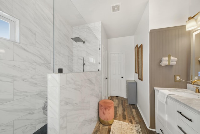 bathroom with wood finished floors, visible vents, vanity, baseboards, and walk in shower