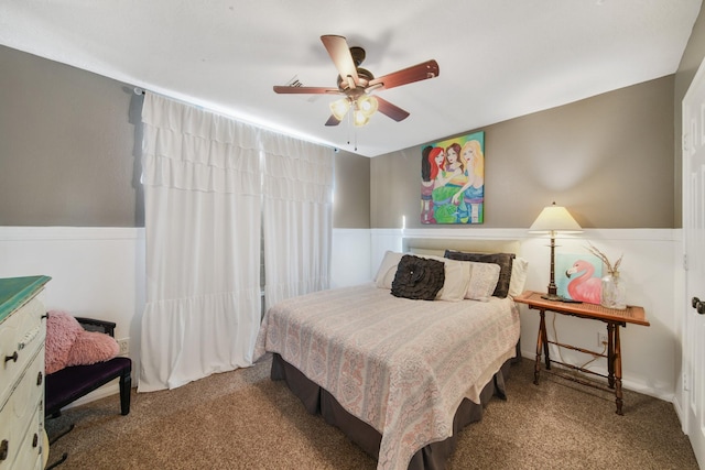 carpeted bedroom with a wainscoted wall and ceiling fan