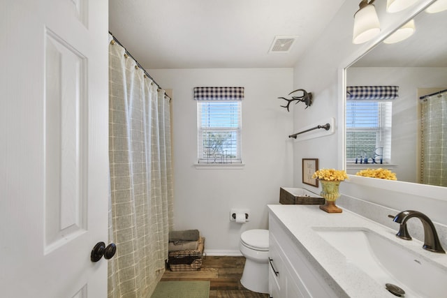 bathroom with toilet, plenty of natural light, visible vents, and wood finished floors