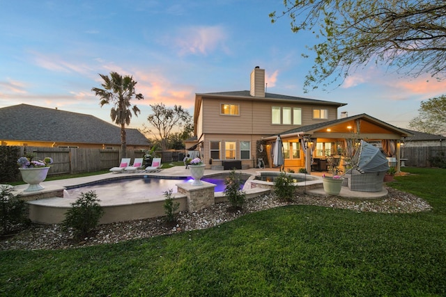 rear view of property with a patio area, a fenced backyard, a yard, and a chimney