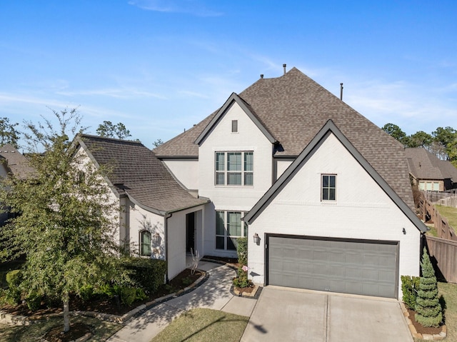 view of front of property featuring driveway, brick siding, roof with shingles, and fence