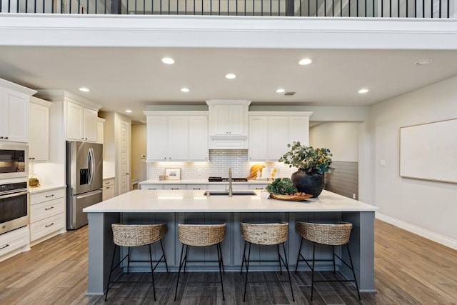 kitchen featuring dark wood-type flooring, a sink, a kitchen breakfast bar, appliances with stainless steel finishes, and a large island