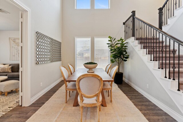 dining room with dark wood-style floors, baseboards, a high ceiling, and visible vents