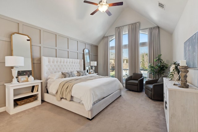 bedroom with light colored carpet, a decorative wall, visible vents, a ceiling fan, and vaulted ceiling