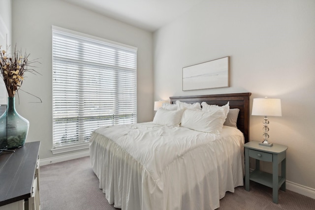 bedroom featuring multiple windows, baseboards, and light colored carpet