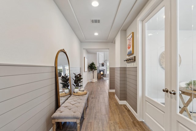 hall featuring recessed lighting, wood finished floors, visible vents, french doors, and wainscoting