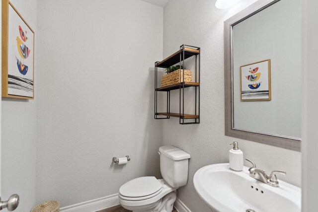 bathroom with baseboards, a sink, and toilet