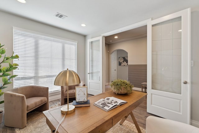 sitting room with arched walkways, a healthy amount of sunlight, visible vents, and wood finished floors