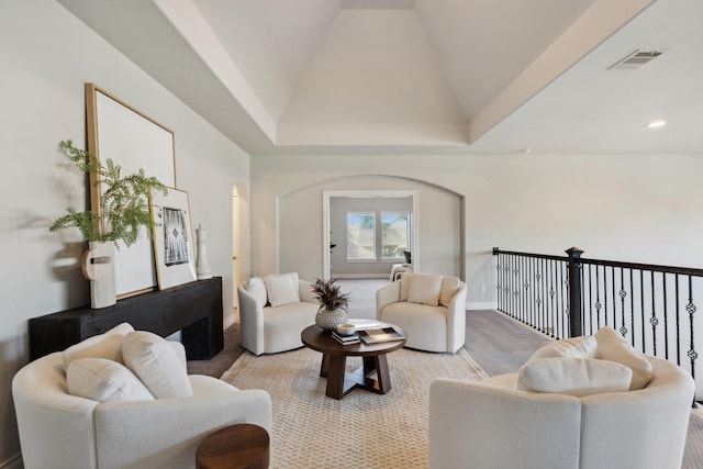 living area with arched walkways, carpet floors, high vaulted ceiling, and visible vents