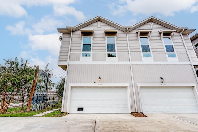 exterior space featuring concrete driveway, an attached garage, and fence