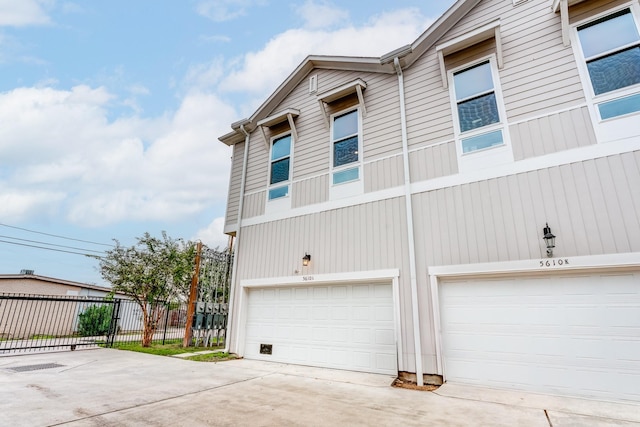 view of side of home with concrete driveway, fence, and an attached garage