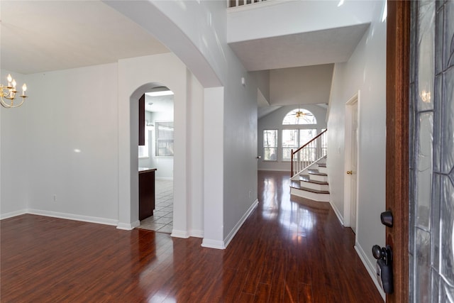 entryway with baseboards, arched walkways, stairway, wood finished floors, and ceiling fan with notable chandelier