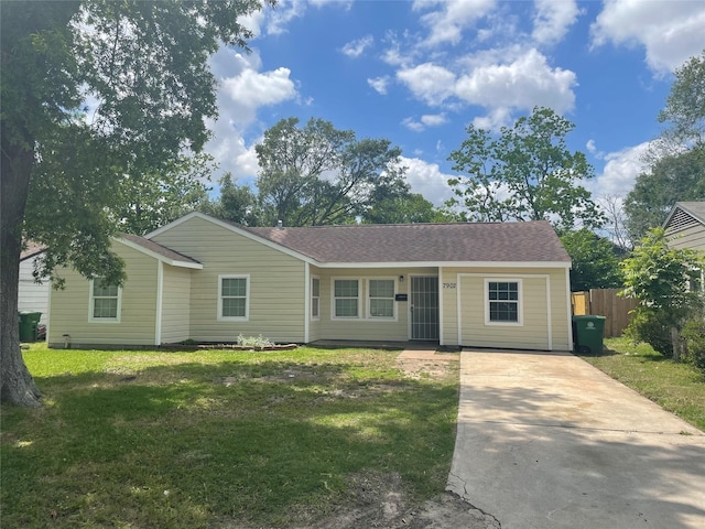 ranch-style house with a shingled roof, fence, concrete driveway, and a front yard