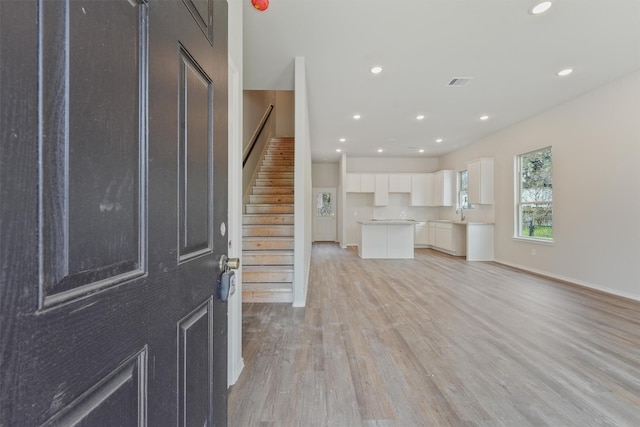 interior space featuring baseboards, visible vents, stairway, light wood-style floors, and recessed lighting