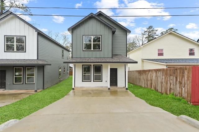 view of front facade featuring board and batten siding, a front lawn, fence, and a shingled roof