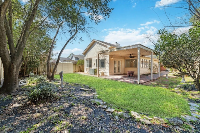 rear view of house with ceiling fan, a patio, fence, french doors, and a lawn