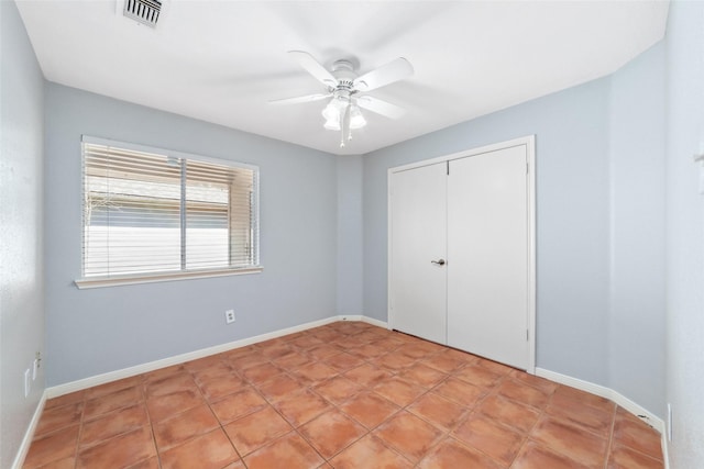 unfurnished bedroom with baseboards, visible vents, ceiling fan, and a closet