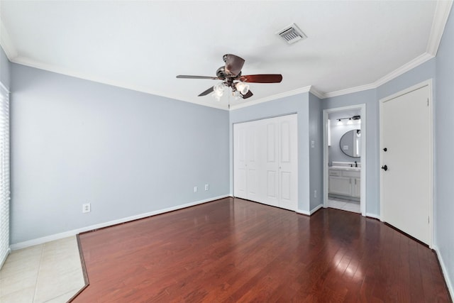 unfurnished bedroom with baseboards, visible vents, ornamental molding, wood finished floors, and a closet