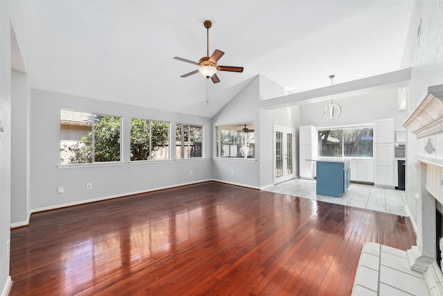 unfurnished living room featuring baseboards, a ceiling fan, a tile fireplace, lofted ceiling, and light wood-type flooring