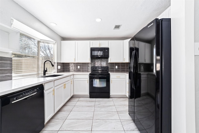 kitchen with visible vents, decorative backsplash, white cabinetry, a sink, and black appliances