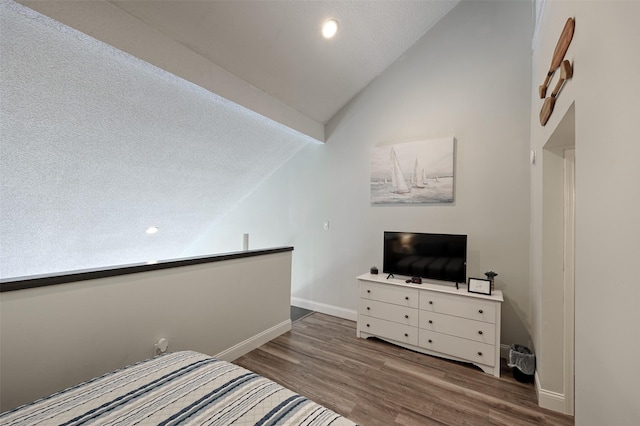 bedroom featuring vaulted ceiling, baseboards, and wood finished floors