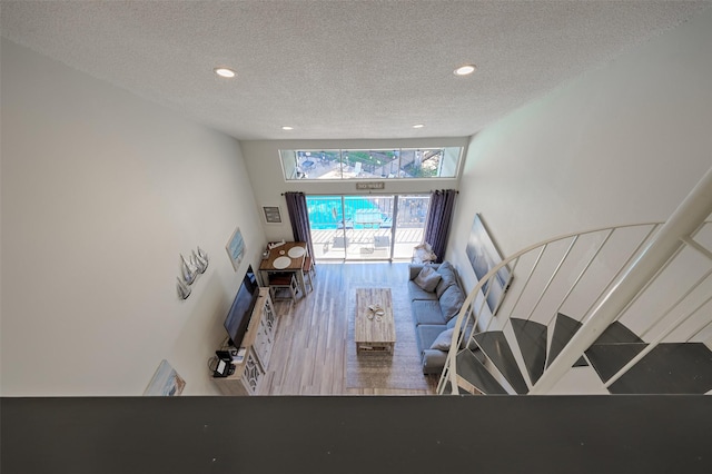 unfurnished living room with a textured ceiling, wood finished floors, and recessed lighting