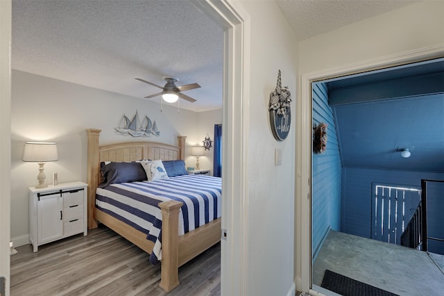 bedroom with a textured ceiling, ceiling fan, and light wood-style floors