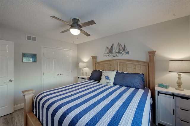 bedroom with a textured ceiling, a ceiling fan, visible vents, light wood-style floors, and a closet