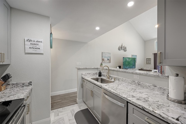 kitchen featuring baseboards, dishwasher, light stone countertops, gray cabinetry, and a sink