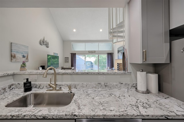 kitchen featuring a sink, light stone countertops, and gray cabinetry