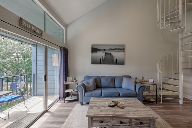 living room featuring stairway, baseboards, high vaulted ceiling, and wood finished floors