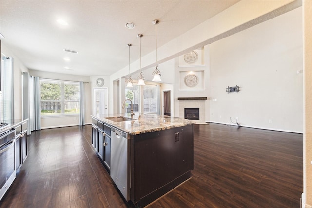 kitchen with dark wood-style floors, a fireplace, visible vents, stainless steel dishwasher, and a sink