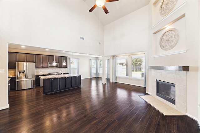 living area with visible vents, lofted ceiling, dark wood-style floors, ceiling fan, and a fireplace