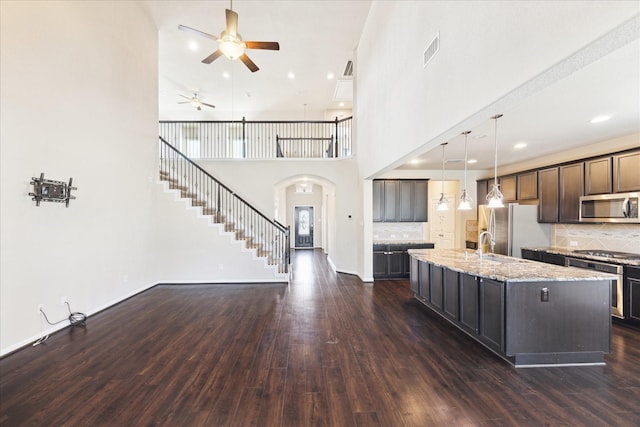 kitchen with light stone counters, appliances with stainless steel finishes, dark wood-style flooring, and visible vents