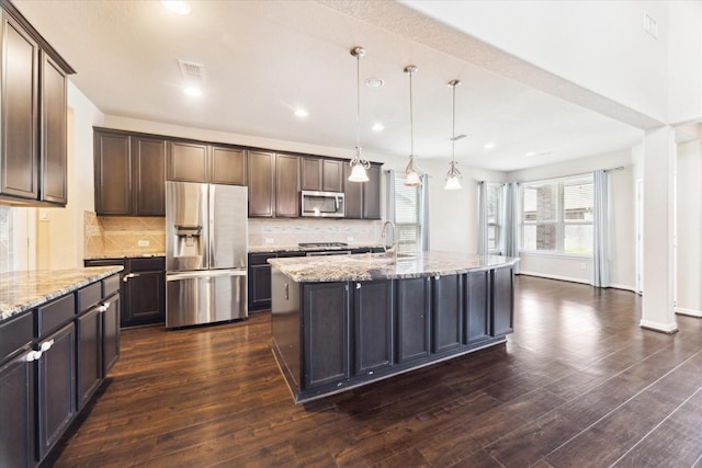 kitchen with light stone counters, appliances with stainless steel finishes, dark wood finished floors, and visible vents