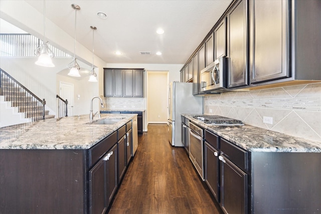 kitchen featuring a kitchen island with sink, a sink, visible vents, appliances with stainless steel finishes, and dark wood-style floors