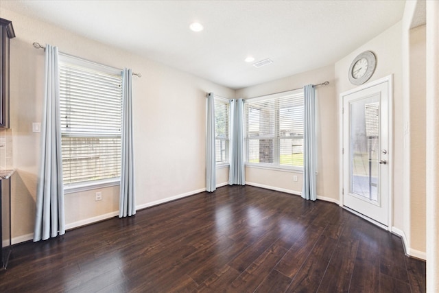 unfurnished room with baseboards, visible vents, dark wood-style flooring, and recessed lighting