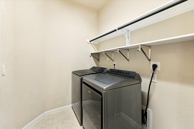 clothes washing area with laundry area, washing machine and clothes dryer, and baseboards