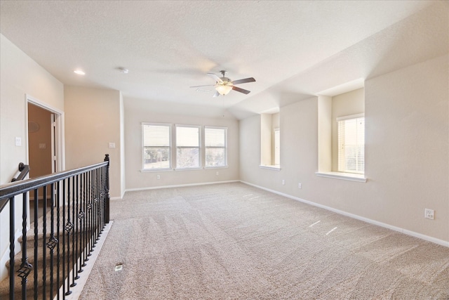 empty room with light carpet, baseboards, and a textured ceiling