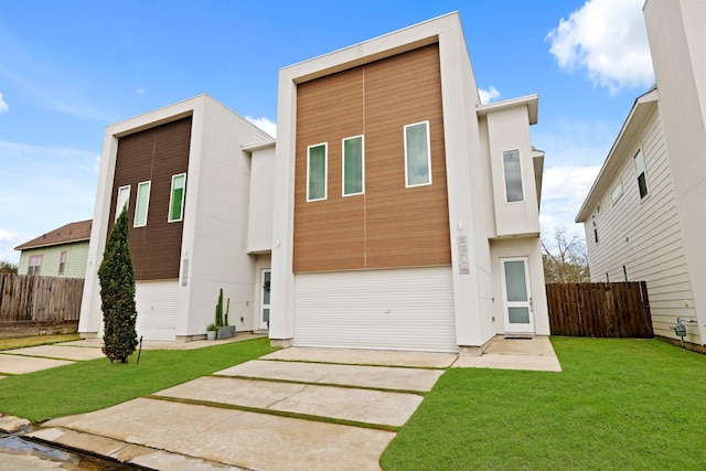 modern home featuring a front yard, fence, and a patio