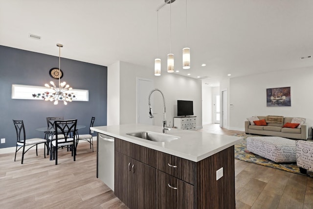 kitchen featuring light wood-style flooring, a sink, open floor plan, dark brown cabinets, and dishwasher