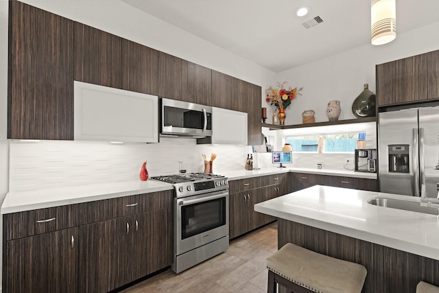 kitchen featuring appliances with stainless steel finishes, light countertops, decorative backsplash, and a kitchen bar