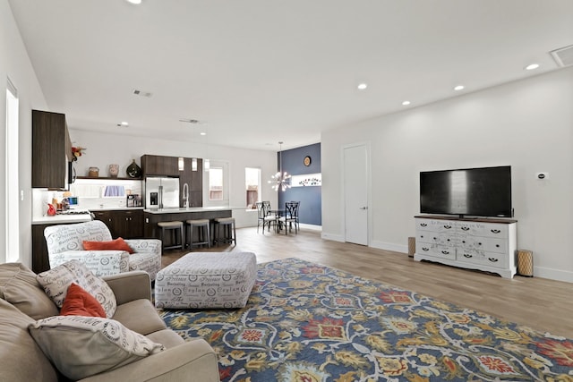 living room featuring baseboards, light wood-style flooring, visible vents, and recessed lighting