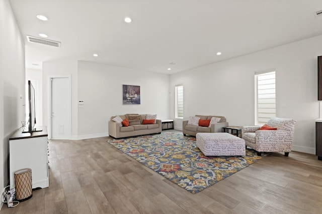 living area featuring a wealth of natural light, visible vents, and wood finished floors