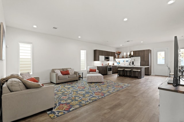 living room with light wood-type flooring, baseboards, visible vents, and recessed lighting